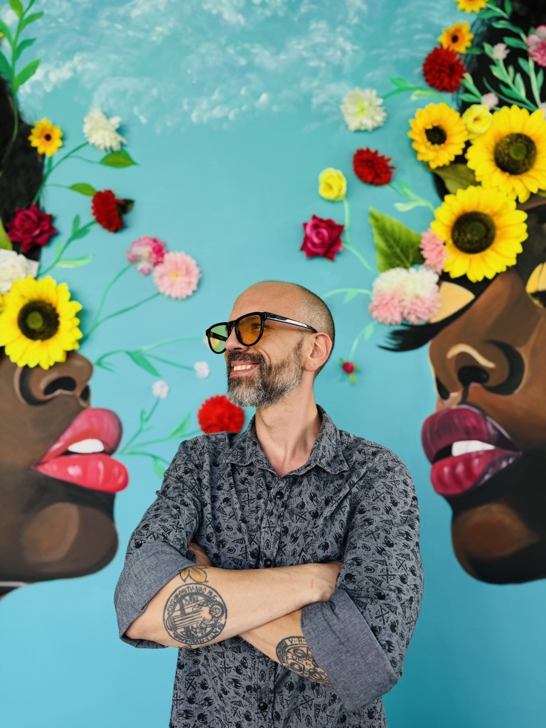 Juan Alejandro Gaviria frente a mural de flores en Medellín